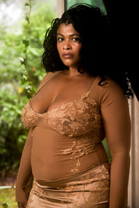 Woman wearing a sheer brown top with a blurred background